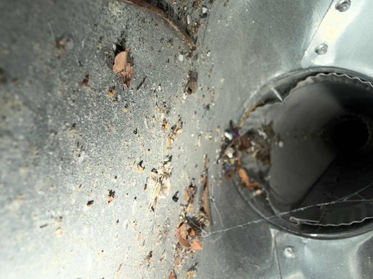 Dirty air duct with debris and cobwebs before cleaning